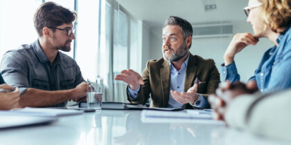 Three professionals sitting around an office table in conversation