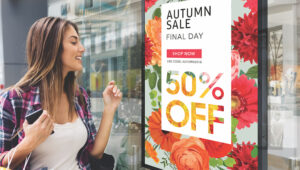 woman shopper looking at retail window display signage advertising sale