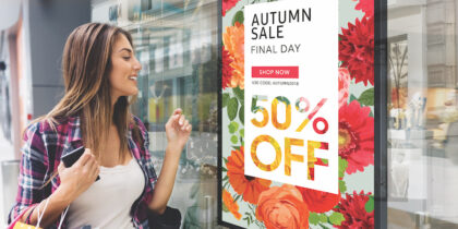 woman shopper looking at retail window display signage advertising sale